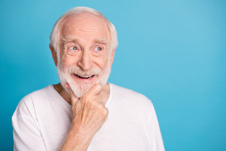 Photo of cheerful aged guy arm on chin look empty space thinking isolated on pastel blue color...