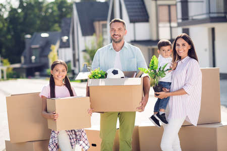 Portrait of four adorable cheerful people dad mom small little kids holding in hands cardboard...