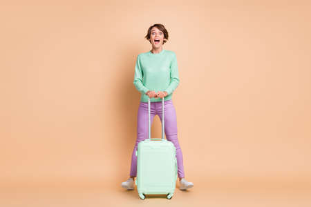 Full size photo of young girl excited amazed surprised trip tourist vacation abroad hold baggage isolated over beige color backgroundの写真素材