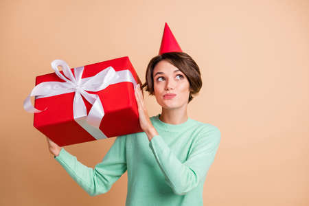 Photo of young attractive girl curious wonder shake present wear party hat look empty space isolated over pastel color backgroundの写真素材