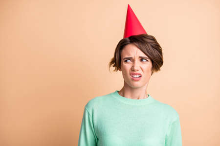Photo of young woman unhappy sad displeased dissatisfied negative wear birthday hat isolated over beige color backgroundの写真素材