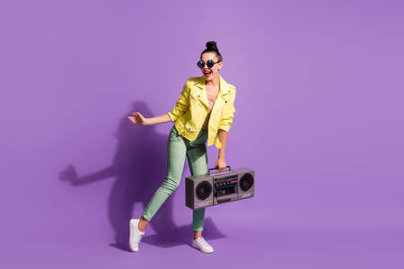 Full body photo of young girl wear style stylish outfit dance enjoy music hold boombox isolated over violet color backgroundの写真素材