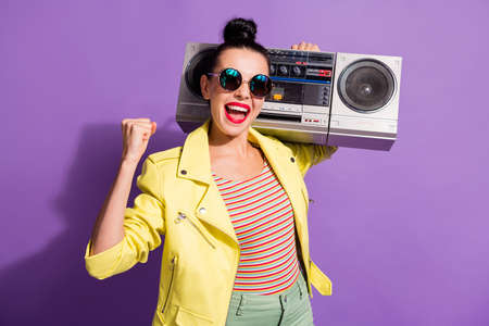 Photo of delighted youth girl hold boom box raise fists scream yeah wear yellow outfit isolated...