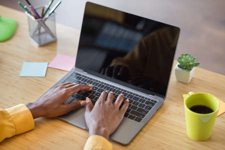 Photo of girl hands typing on laptop table wear yellow shirt at homeの写真素材