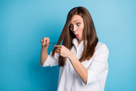 Photo of hairdresser lady changing style hold scissors see split ends cut hair wear white shirt isolated blue color backgroundの写真素材
