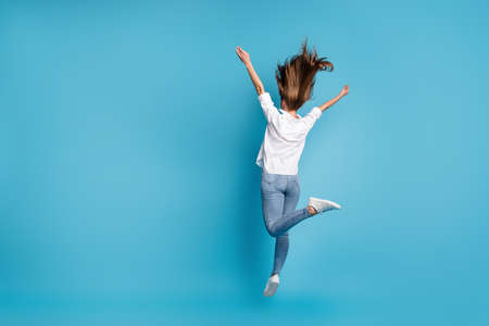 Full length rear behind view photo of lady jump high up raise arms wear white shirt jeans shoes...