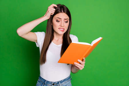 Portrait of pretty confused young lady read book touch head wear casual t-shirt isolated on green backgroundの写真素材