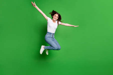 Full size photo of cheerful girl jump hold hands plane fly game concept isolated over green color backgroundの写真素材