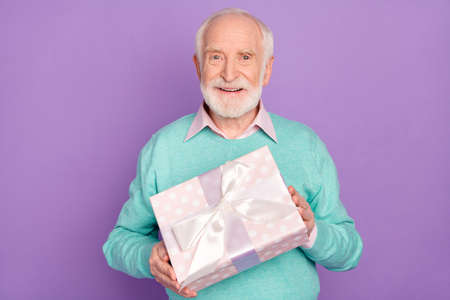 Photo portrait of senior man keeping gift box with present birthday party smiling happy cheerful isolated on pastel purple color backgroundの写真素材