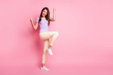 Full body photo of ecstatic lady raise fists knee wear casual isolated on pink color background
