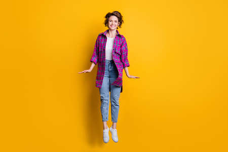 Full length photo of charming optimistic girl jump up air free time isolated on yellow color...