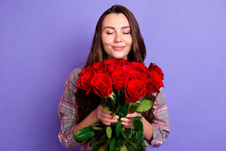 Photo of joyful peaceful young charming lady smell flowers roses gift celebrate holiday isolated on violet color backgroundの写真素材