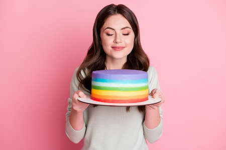 Photo of attractive wavy hairdo lady arms hold cake smelling closed eyes isolated on pastel pink backgroundの写真素材