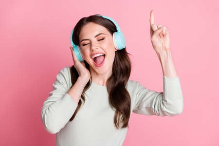 Portrait of astonished funny person open mouth hand on headphones finger up isolated on pink color...