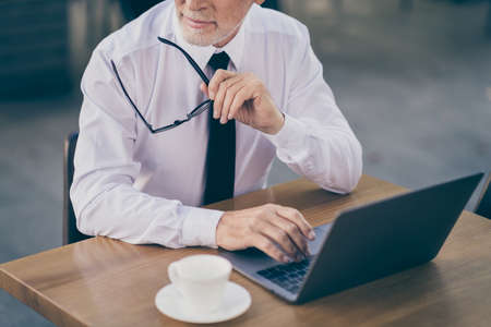 Photo of optimistic old business man write laptop hold spectacles wear white shirt outdoors near work centerの写真素材