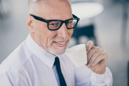 Photo of attractive smiling mature worker man wear formal shirt eyeglasses drinking beverage cafeteria outdoors city streetの写真素材