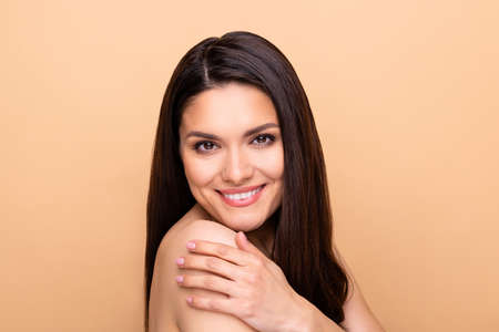 Profile portrait of nice optimistic brunette long hairdo lady hand shoulder without clothes isolated on pastel beige color backgroundの写真素材