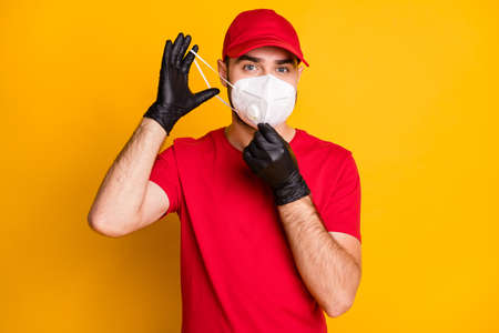 Portrait of healthy mailman putting n95 respirator on mers cov stop pandemia concept isolated on bright yellow color backgroundの写真素材