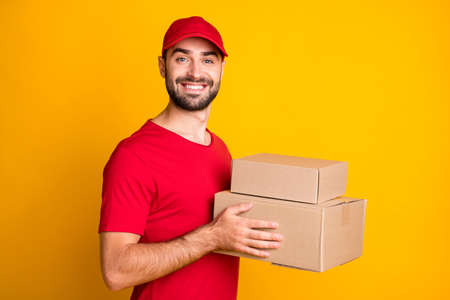 Profile side view portrait of nice content cheerful guy mailman holding in hands parcels fast bring isolated over bright yellow color backgroundの写真素材