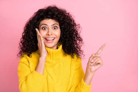 Photo of young excited latin girl amazed surprised indicate finger empty space promo recommend sale isolated over pastel color backgroundの写真素材