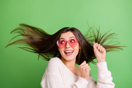 Photo of young beautiful happy positive excited smiling girl dancing with flying hair isolated on green color backgroundの写真素材
