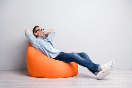 Full body profile side photo of man happy positive smile sit bag rest relax look empty space isolated over grey color backgroundの写真素材