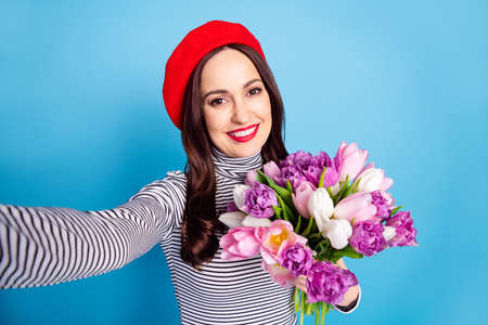 Photo portrait of woman taking selfie smiling keeping tulips bouquet isolated vivid blue color...