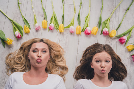 Top above high angle view photo of mother and daughter lie floor send air kiss flowers tulips indoors inside houseの写真素材