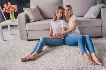 Full length photo of mother and daughter child sit floor smile good mood wear casual clothes indoors inside houseの写真素材