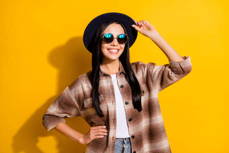 Photo of young attractive girl happy positive smile wear hat sunglasses isolated over yellow color...