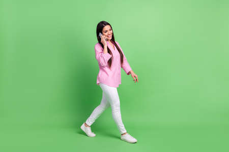 Full length body size view of attractive cheerful girl going talking on phone operator roaming...