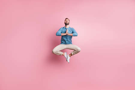 Full length photo of sweet peaceful young guy wear blue pullover jumping enjoying yoga isolated pink color backgroundの写真素材