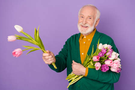 Portrait of cheerful person arm raise flower to you toothy smile isolated on purple color backgroundの写真素材
