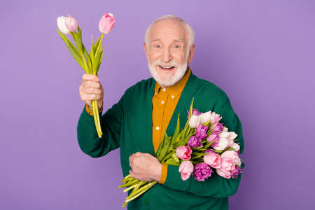 Photo of positive aged person raise hand with flower look camera isolated on violet color background