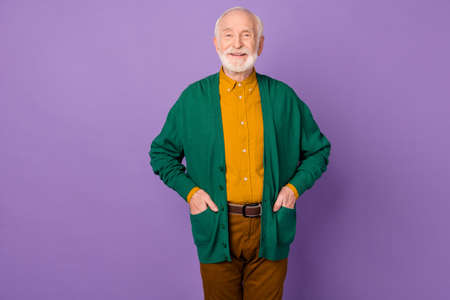 Photo of satisfied man put hands in pockets beaming smile look camera isolated on violet color backgroundの写真素材