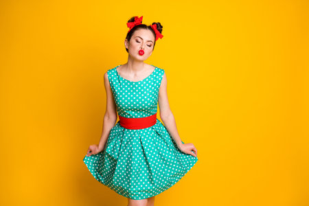 Portrait of nice glamorous dreamy girl wearing dotted teal dress posing sending you air kiss isolated over vivid yellow color backgroundの写真素材