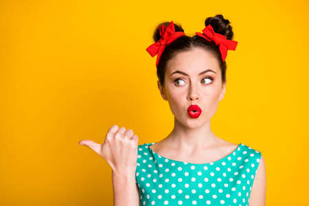 Close-up portrait of lovely glamorous amazed girl showing copy space pout lips isolated over bright yellow color backgroundの写真素材