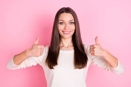 Photo of satisfied friendly girl toothy smile show two hands thumbs up isolated on pink color backgroundの写真素材