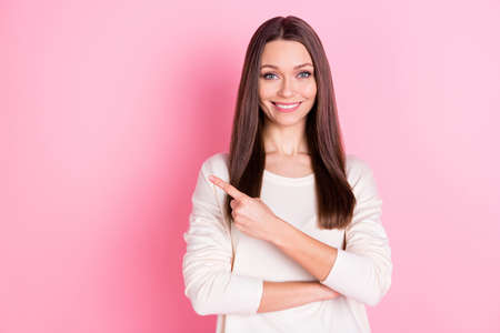 Portrait of pretty positive girl toothy smile direct finger empty space proposition isolated on pink color backgroundの写真素材