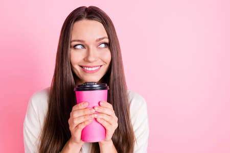 Portrait of attractive cheerful lady arms hold coffee look interested empty space isolated on pink color backgroundの写真素材