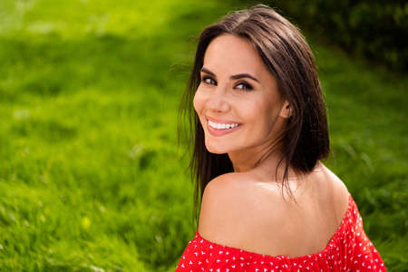 Profile side photo of pretty adorable young woman dressed red off-shoulders dress sitting green grass smiling outdoors backyardの写真素材