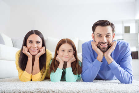 Photo of young happy positive good mood family mother father and daughter lying on floor hold hands...