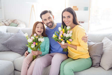 Photo of happy family hug cuddle enjoy time together positive smile girls hold flowers bouquet...