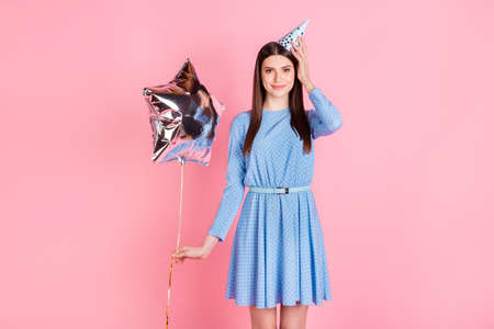 Photo of young beautiful smiling girl with cone on head celebrate birthday hold balloon isolated on pink color backgroundの写真素材