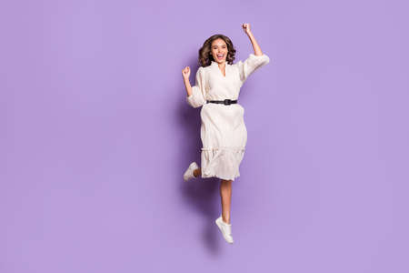 Full length body size photo of girl smiling jumping high gesturing like winner isolated on pastel purple color backgroundの写真素材