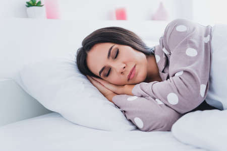 Photo of gorgeous young person lying closed eyes arms palms under head have good sleep home indoorsの写真素材