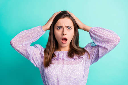 Portrait of impressed sad nice girl hand hair open mouth wear purple shirt isolated on blue color backgroundの写真素材