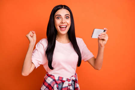 Portrait of astonished funny lady fist up open mouth celebrate success isolated on orange color backgroundの写真素材