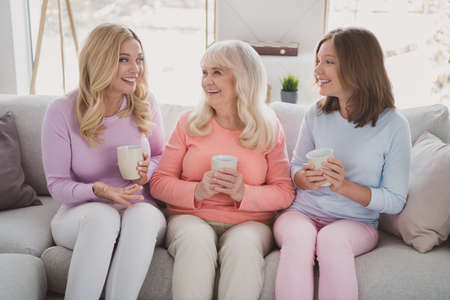 Photo portrait of granny mother daughter drinking tea sitting on couch laughing talking