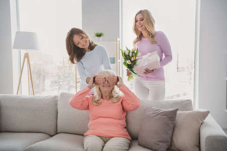 Photo portrait of granddaughter closing eyes granny making surprise with mother giving flowers bunch...